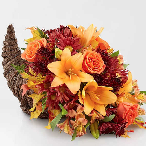 Autumn bouquet with orange lilies, roses, and burgundy mums in a woven cornucopia