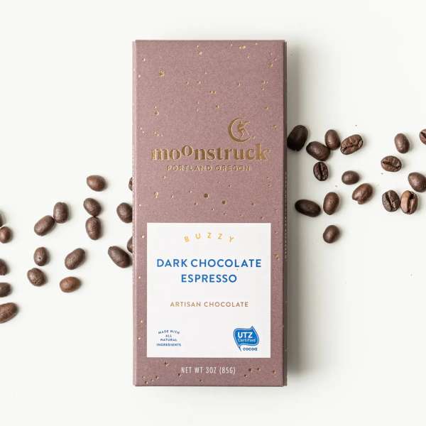 Box of dark chocolate espresso with coffee beans scattered around it