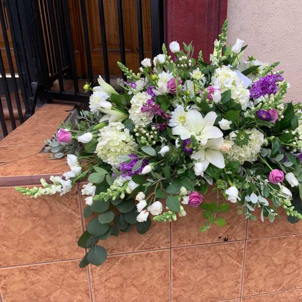 Large floral arrangement with white lilies, roses, and purple blooms