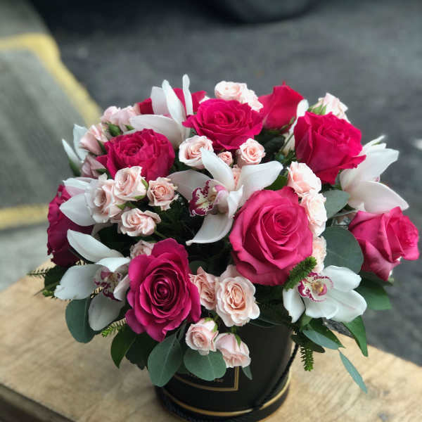 Bouquet of hot pink and pale pink roses with white orchids in a black box