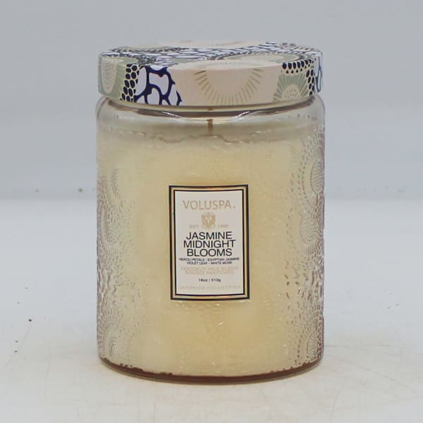 A jasmine-scented candle in a glass jar with a patterned lid