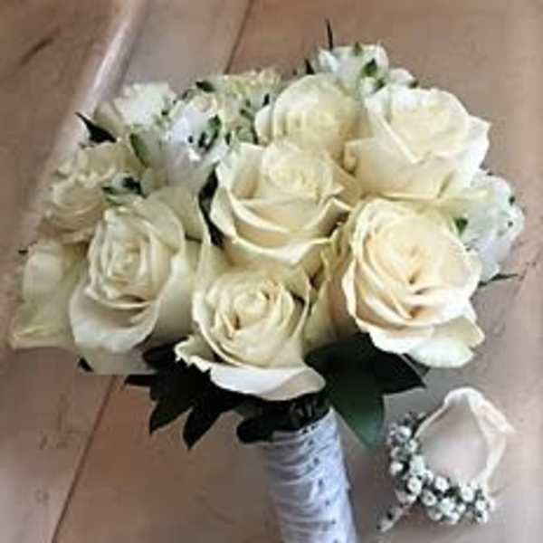 Bridal hand-tied bouquet of ivory roses with wrapped handle and matching single-rose boutonniere.