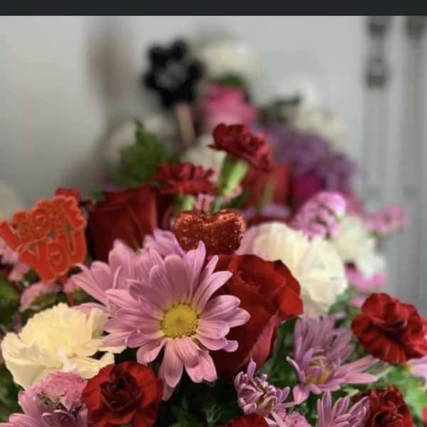 Mixed pink, red, and white flowers in a white "Bee Mine" container