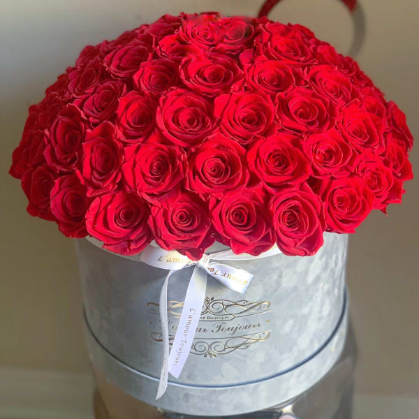 Large bouquet of red roses in a round hat box with a ribbon