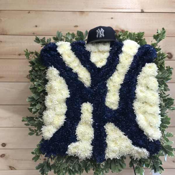 Large floral tribute in navy and white with a baseball cap on top