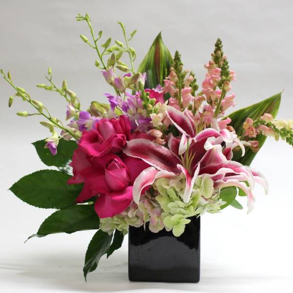 Pink lilies and roses in a black square vase