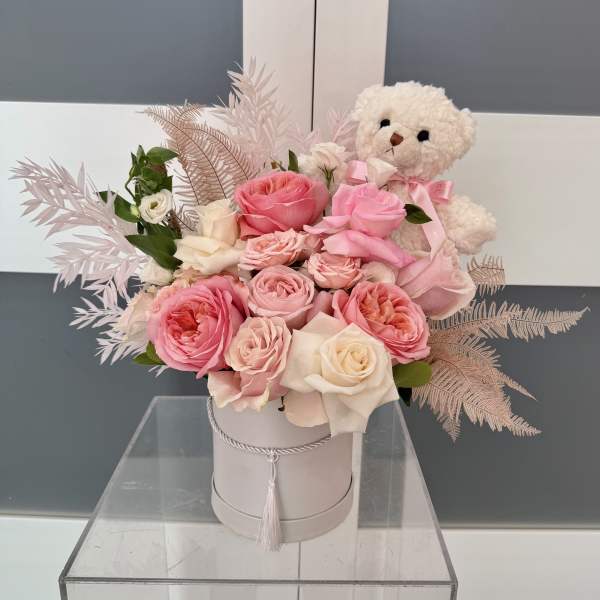 Pink and white roses in a round box with a teddy bear