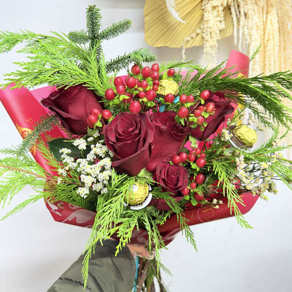 Bouquet of red roses with berries and greenery wrapped in red paper