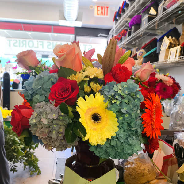 Mixed bouquet of roses, gerbera daisies, and hydrangeas in a vase