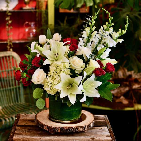 White lilies and red roses arranged in a green vase