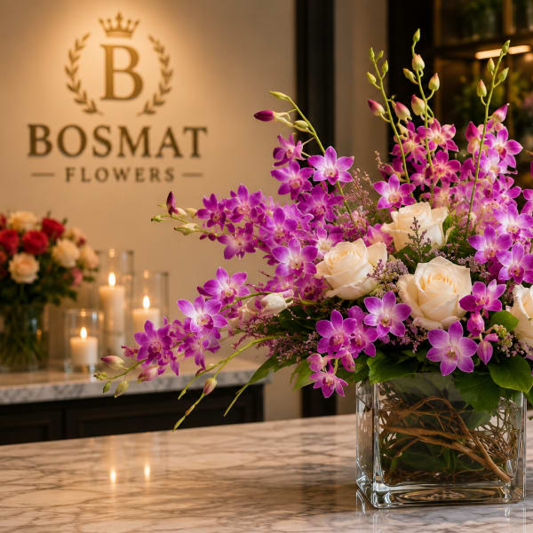 Purple orchids and white roses arranged in a clear glass vase