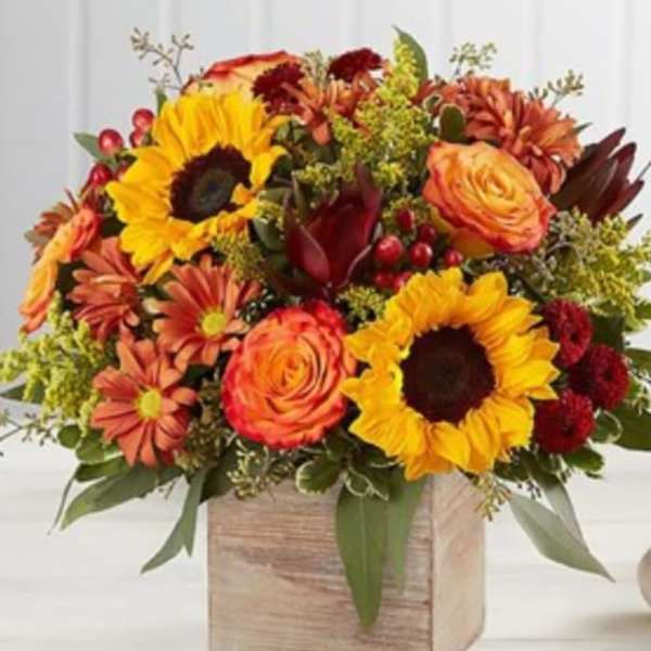 Autumn bouquet with sunflowers, roses, and daisies in a wooden box