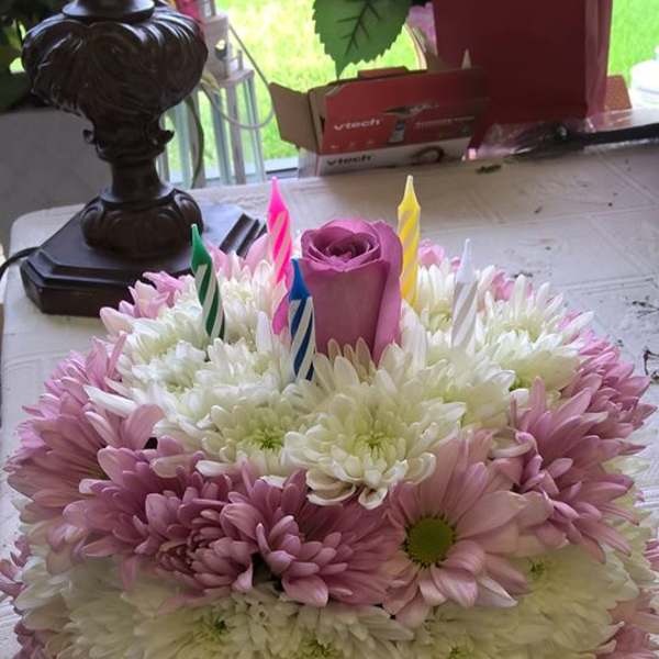 Round bouquet of pink and white daisies with a purple rose and birthday candles