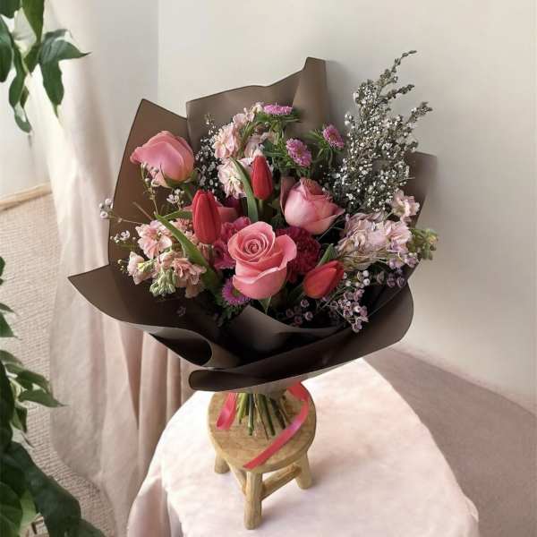 Pink and red mixed bouquet wrapped in dark paper