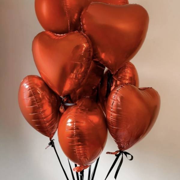 Cluster of red heart-shaped balloons tied with black ribbons