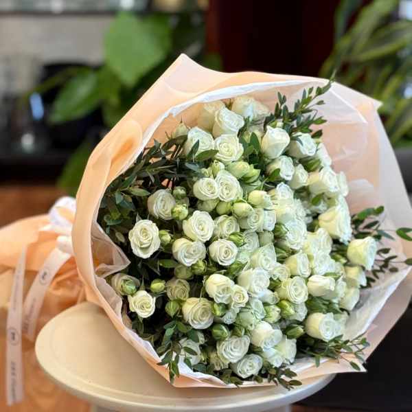 Bouquet of white spray roses wrapped in pale peach paper