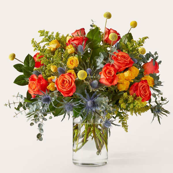 Mixed bouquet of orange and yellow roses in a clear glass vase