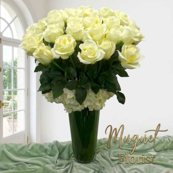 Tall vase arrangement of pale yellow roses with white flowers