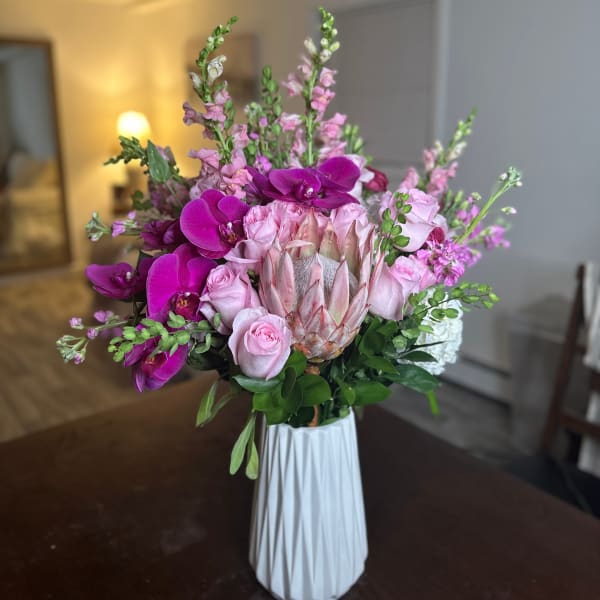 Pink and purple floral arrangement in a white vase