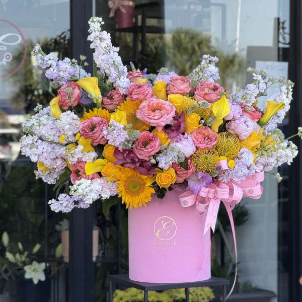 Large pink box arrangement with roses, yellow calla lilies, and lavender blooms