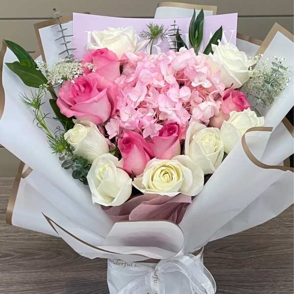 Pink and white rose bouquet with hydrangea in white wrapping