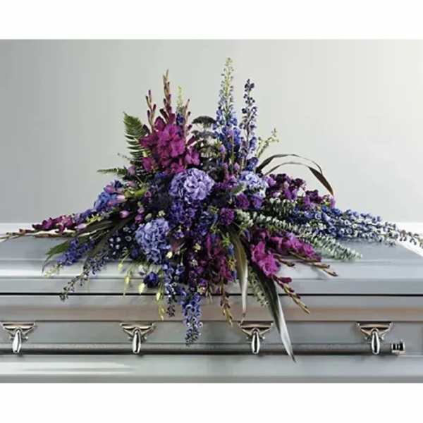 Purple and blue floral spray on a silver casket