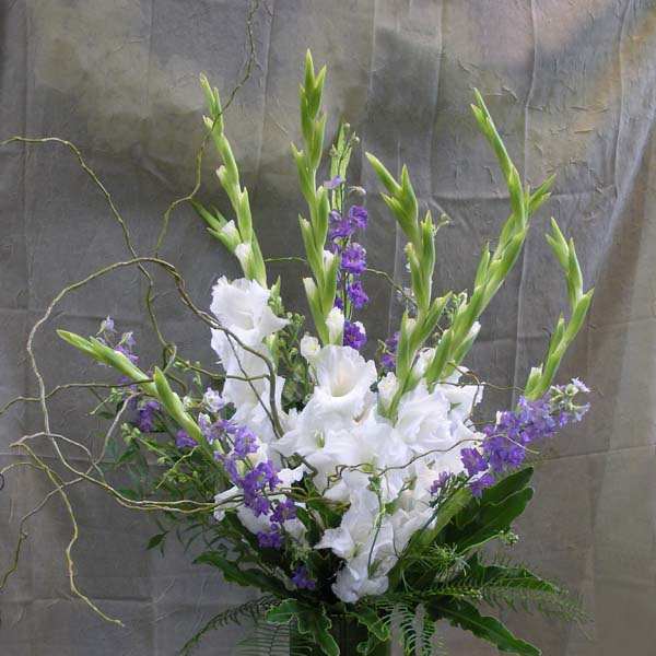 Tall white and purple floral arrangement in a glass vase