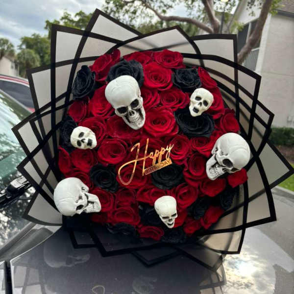 Red and black rose bouquet with skull decorations and a birthday topper