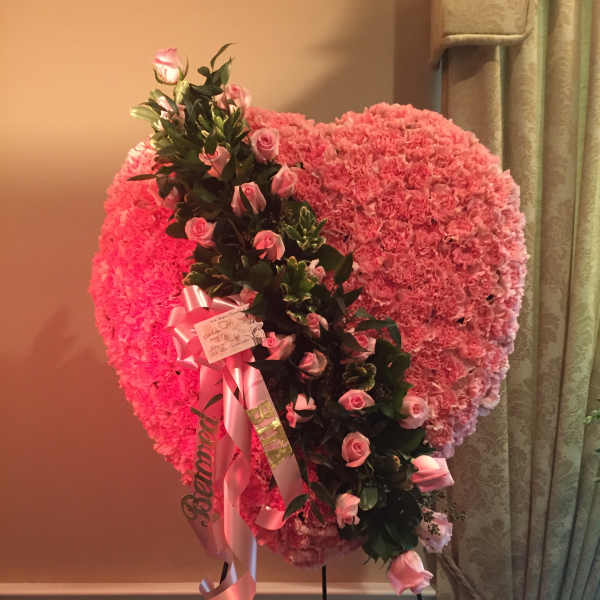 Pink heart-shaped floral standing arrangement with roses and ribbons