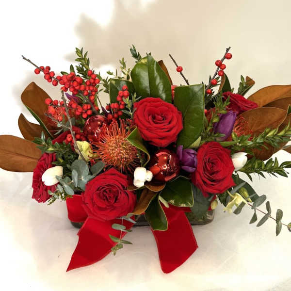 Red roses arranged with berries and a red ribbon
