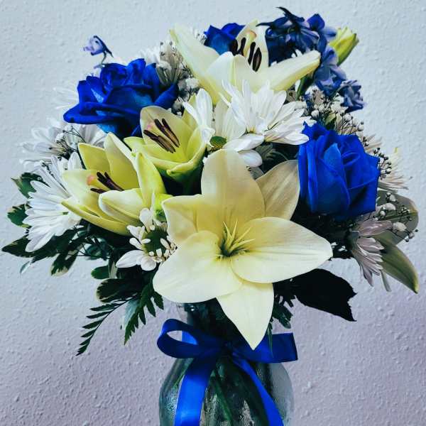 Bouquet of blue roses, white daisies, and pale lilies in a glass vase