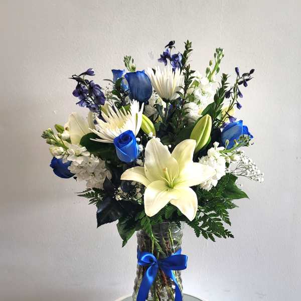 Blue and white bouquet with lilies and roses in a glass vase