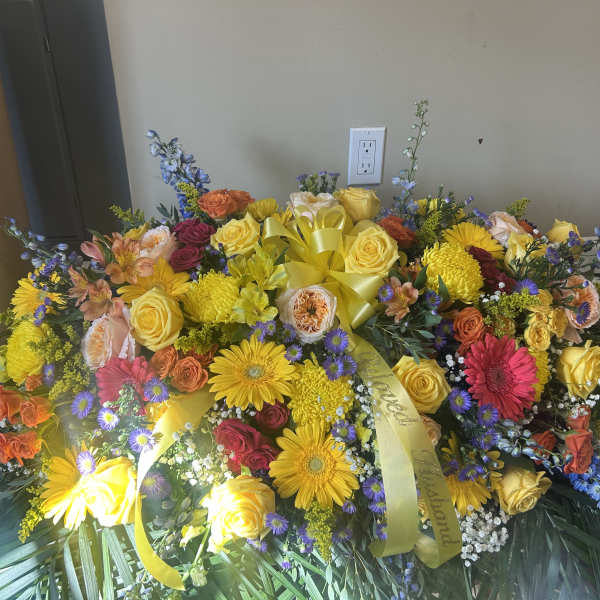 Large colorful floral spray with roses, daisies, and ribbon
