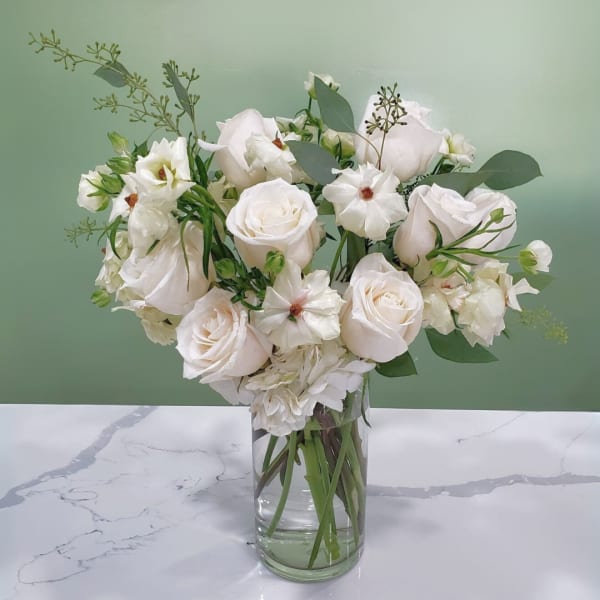 White roses and small white blooms in a clear glass vase