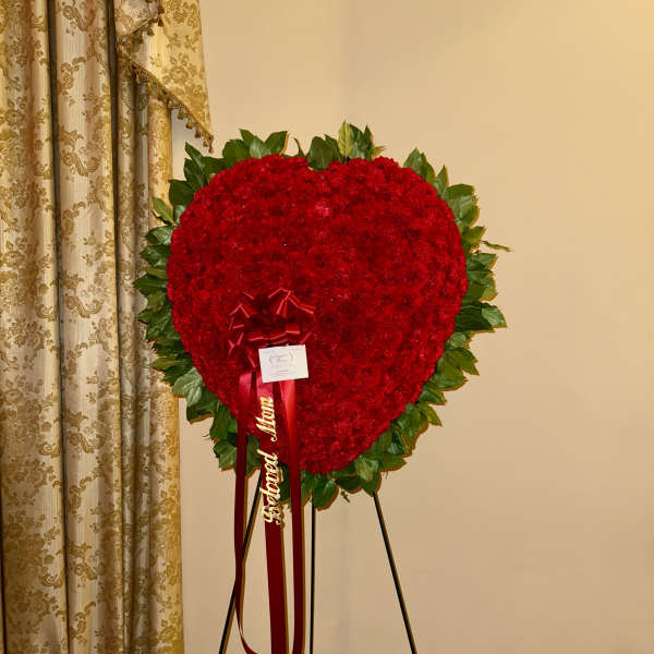 Heart-shaped red floral standing tribute on an easel with ribbon