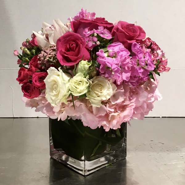 Pink and white rose bouquet in a square glass vase