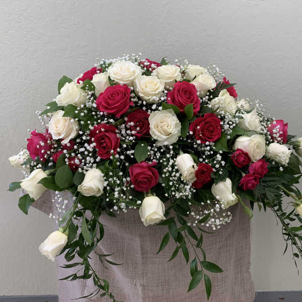 Arrangement of red and white roses with baby's breath in a fabric-covered container