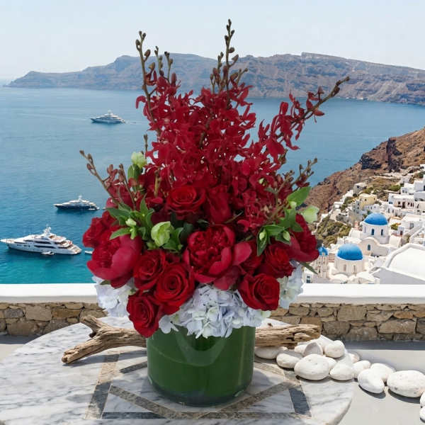Red floral arrangement in a green vase with a seaside backdrop