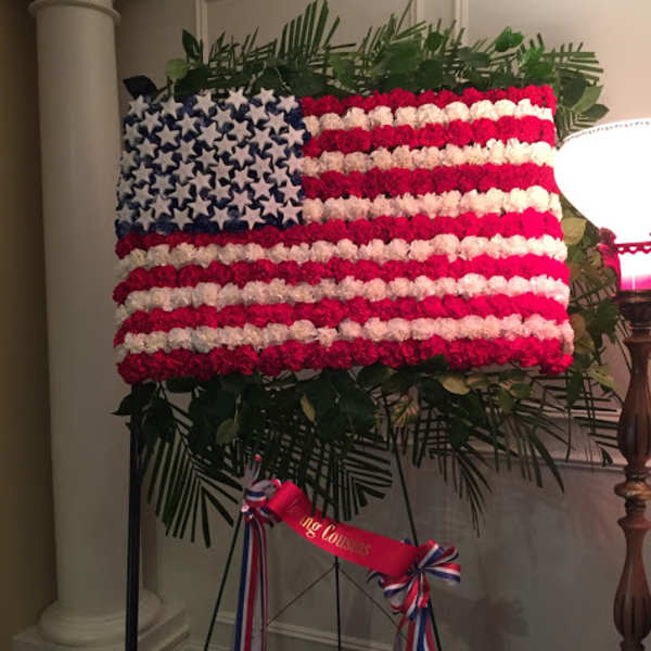 Floral American flag display on an easel with red, white, and blue flowers