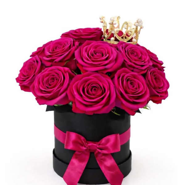 Hot pink roses in a black hat box with a pink ribbon and small crown