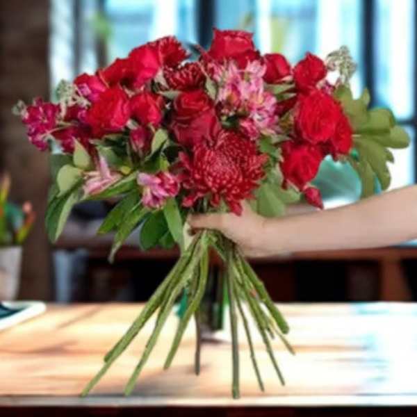 Bouquet of red roses and pink flowers being held by hand