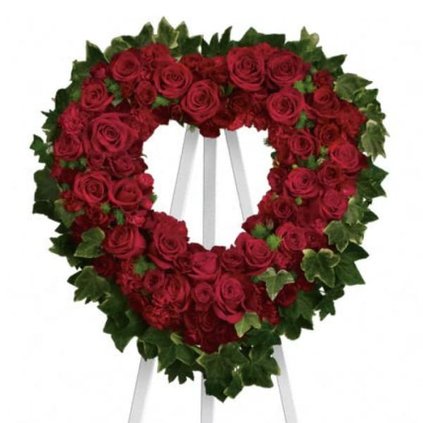 Heart-shaped wreath of red roses on a white easel