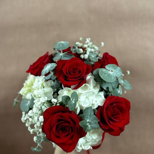 Handheld bouquet of red roses and white hydrangeas with eucalyptus
