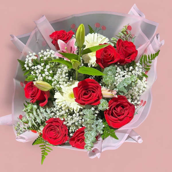 Bouquet of red roses and white flowers wrapped in pink paper