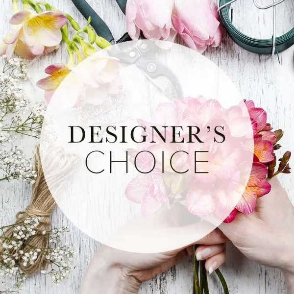 Hands holding a pink floral bouquet with a designer's choice label