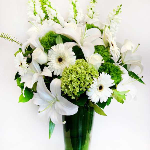 White lilies and gerbera daisies in a green glass vase