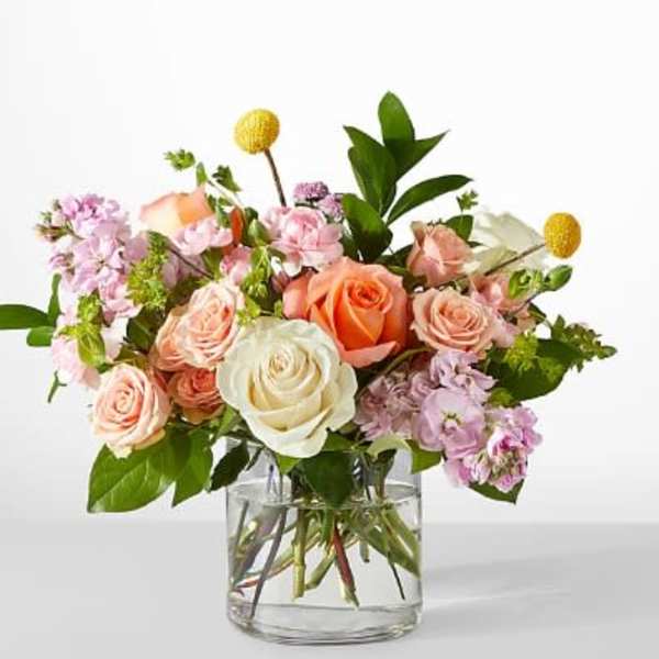 Mixed bouquet of roses and pink blooms in a clear glass vase