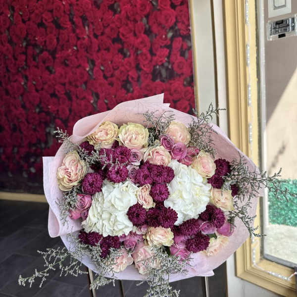 Bouquet of pink and white roses with magenta carnations in pale pink wrap