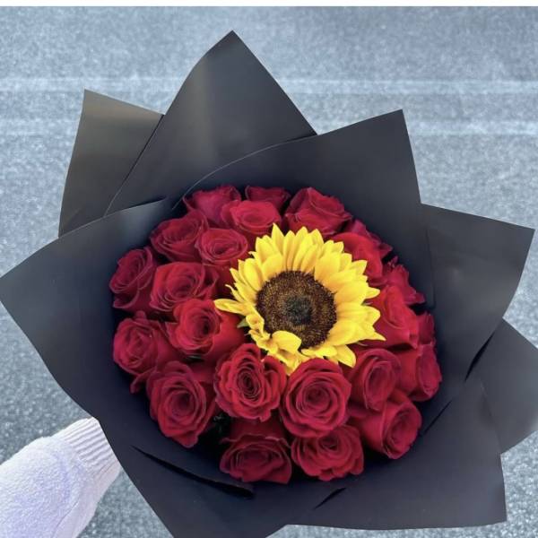 Bouquet of red roses with a yellow sunflower in black wrap