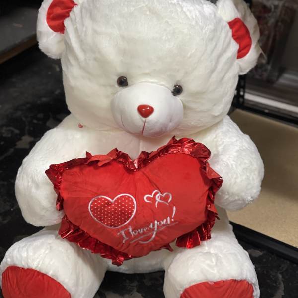 White teddy bear holding a red heart with "I love you" text